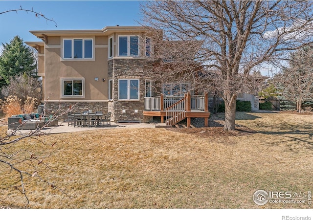 back of property featuring stone siding, stairway, a lawn, stucco siding, and a patio area