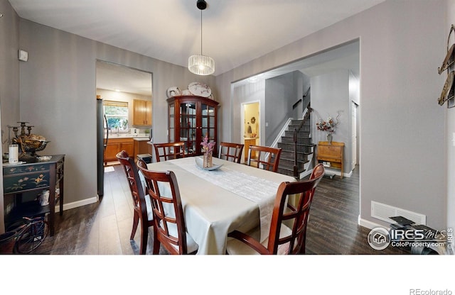 dining area featuring stairway, baseboards, visible vents, and dark wood-style flooring