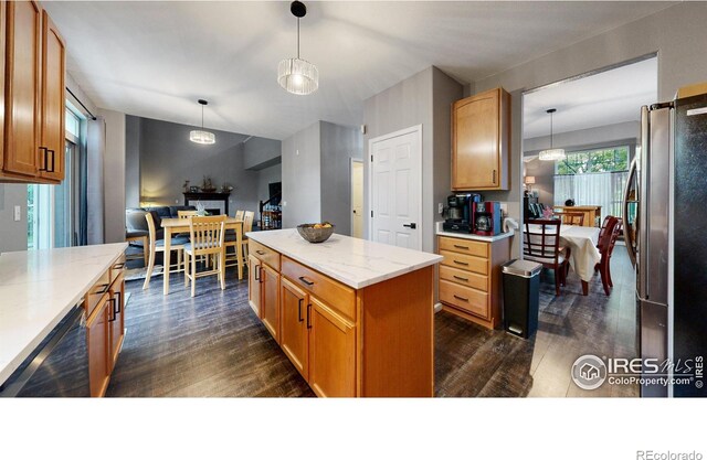 kitchen with black dishwasher, freestanding refrigerator, a kitchen island, and decorative light fixtures