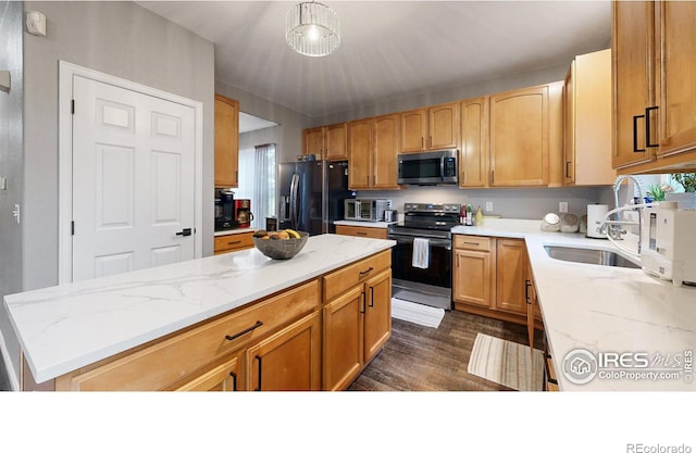 kitchen featuring a kitchen island, appliances with stainless steel finishes, light stone counters, and a sink