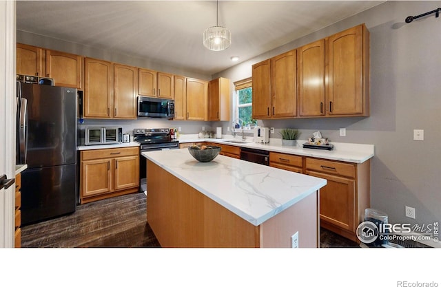 kitchen with dark wood finished floors, a kitchen island, decorative light fixtures, stainless steel appliances, and a sink