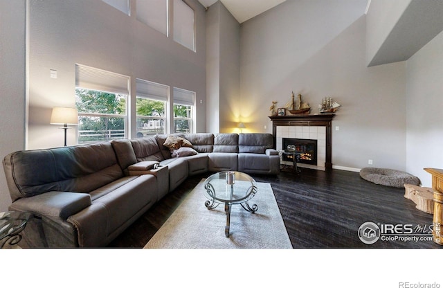 living area featuring dark wood-style flooring, a tile fireplace, and baseboards