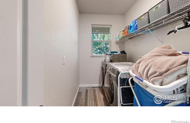 laundry area with a textured wall, laundry area, wood finished floors, baseboards, and independent washer and dryer