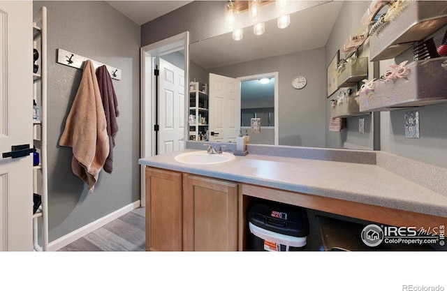 bathroom featuring baseboards, wood finished floors, and vanity