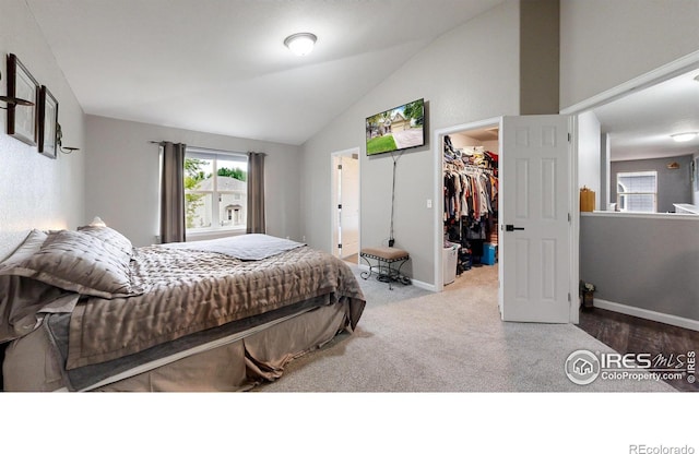 bedroom featuring vaulted ceiling, a spacious closet, a closet, and baseboards