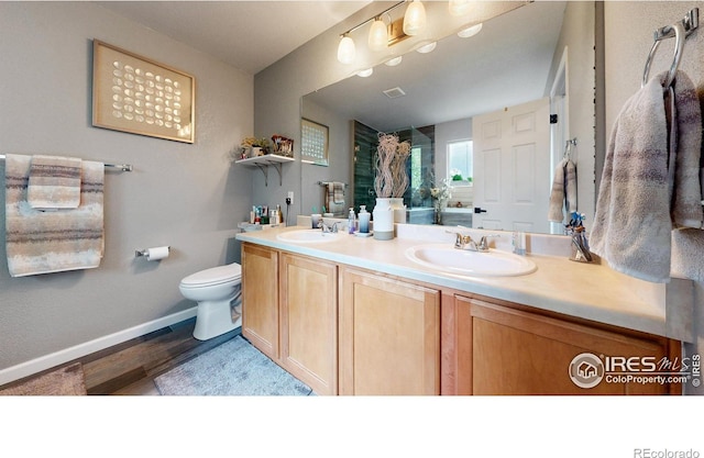 bathroom featuring double vanity, wood finished floors, a sink, and baseboards