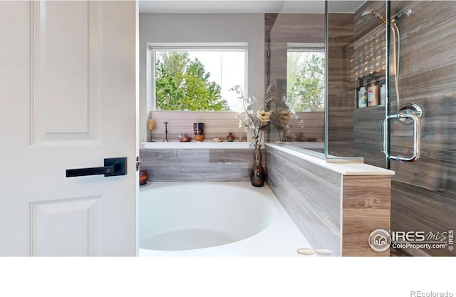 full bathroom featuring a garden tub and a wealth of natural light