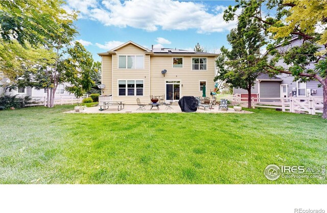 rear view of property featuring fence private yard, a patio area, solar panels, and a yard