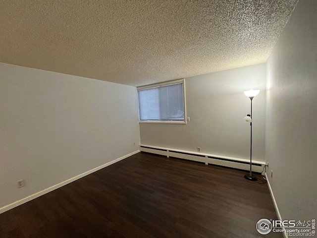 empty room with dark wood-style floors, a textured ceiling, a baseboard radiator, and baseboards