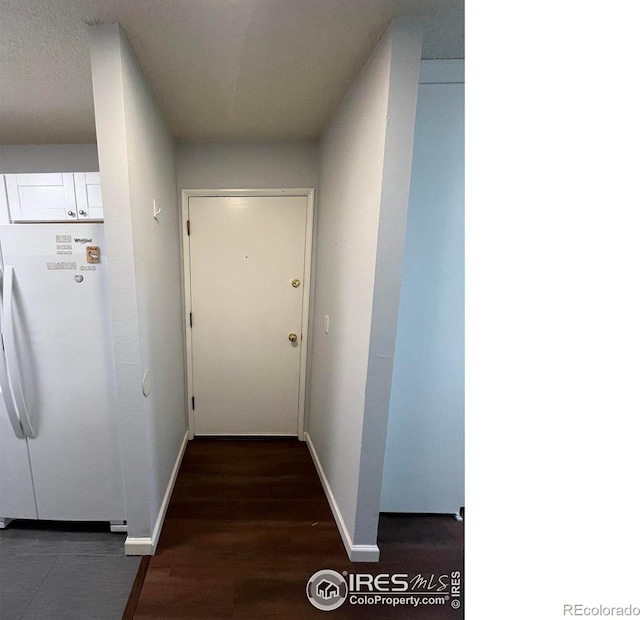 corridor with dark wood-type flooring and baseboards