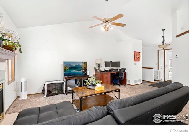 living room with high vaulted ceiling, a glass covered fireplace, visible vents, and light colored carpet