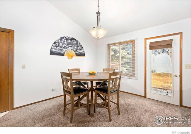 carpeted dining room featuring vaulted ceiling and baseboards