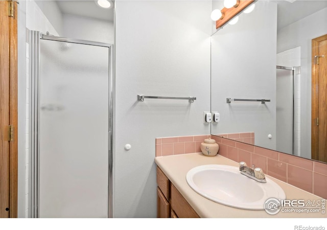 full bath with tasteful backsplash, a stall shower, and vanity