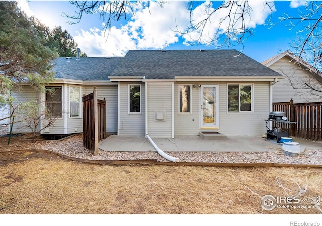 back of house with roof with shingles, a patio, and fence