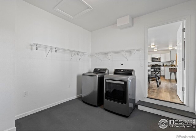 laundry room with attic access, laundry area, washer and clothes dryer, and baseboards