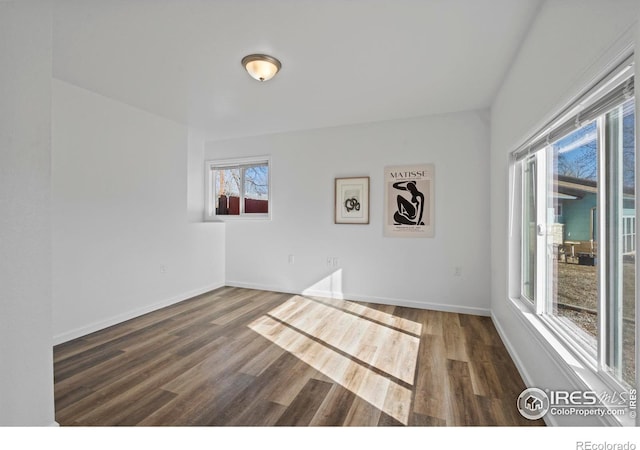 spare room featuring baseboards and dark wood-type flooring