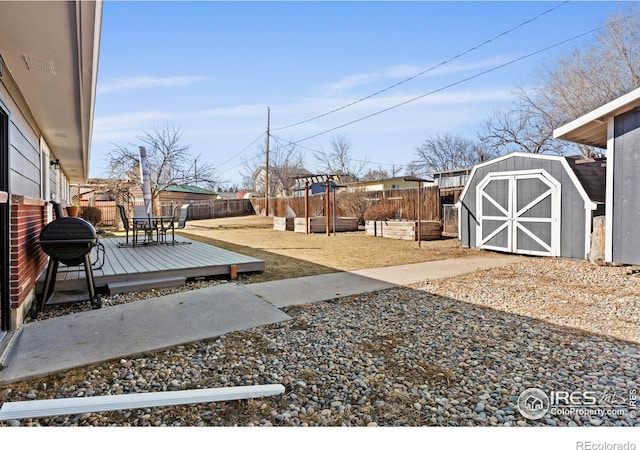 view of yard with a fenced backyard, a shed, a garden, an outdoor structure, and a wooden deck