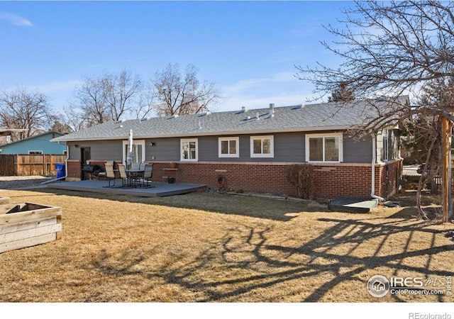 back of property with a yard, brick siding, a patio area, and fence