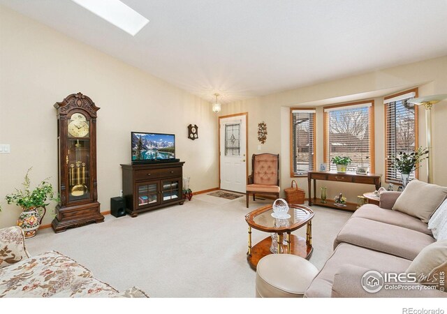 living room featuring a skylight, carpet flooring, and baseboards