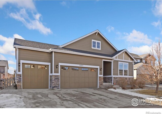 craftsman house featuring an attached garage, stone siding, and driveway