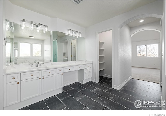 full bath featuring a textured ceiling, visible vents, vanity, and baseboards