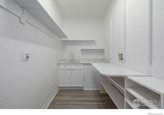 interior space with hookup for a washing machine, cabinet space, dark wood-type flooring, a sink, and baseboards