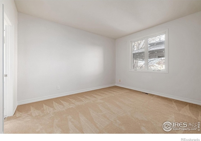 spare room with carpet floors, visible vents, and baseboards