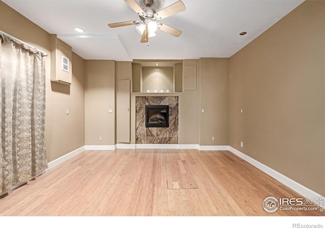 unfurnished living room featuring light wood finished floors, ceiling fan, baseboards, and a high end fireplace