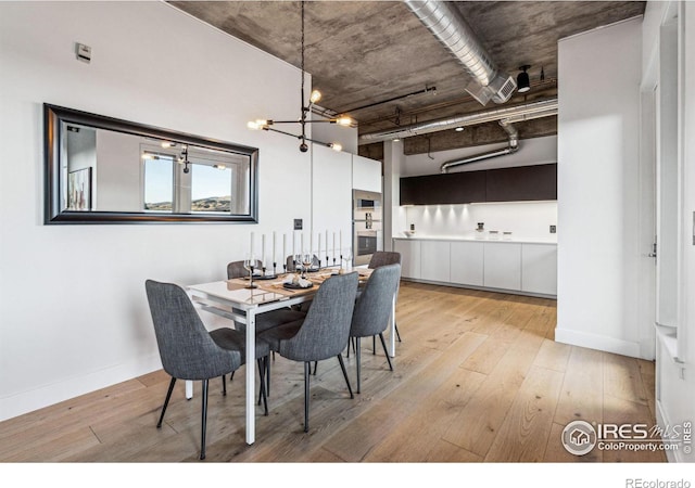 dining space featuring light wood finished floors, baseboards, and a chandelier