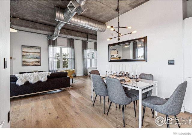 dining area with a chandelier, visible vents, and light wood-style flooring