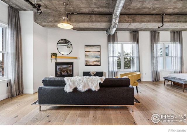 living area with light wood-type flooring, a glass covered fireplace, and baseboards