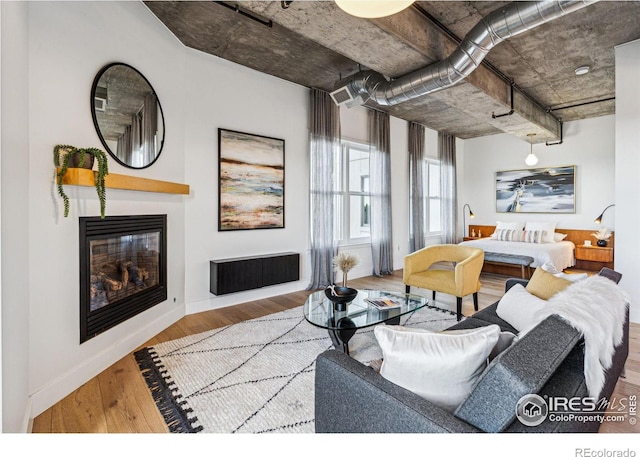 living room featuring light wood finished floors, a glass covered fireplace, and baseboards