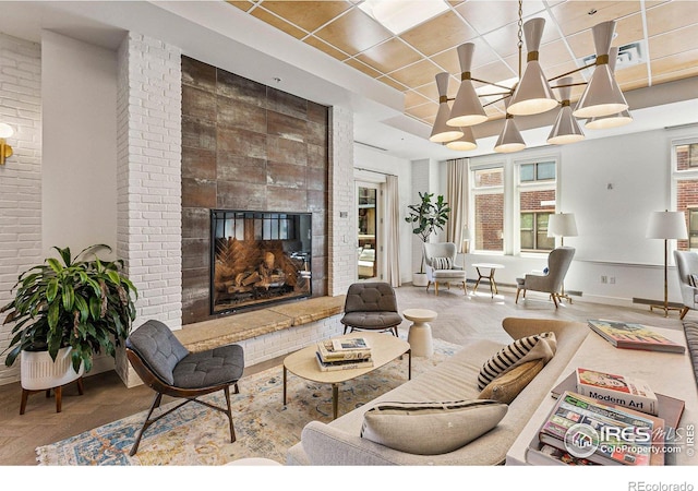 living area with brick wall, a fireplace, and baseboards