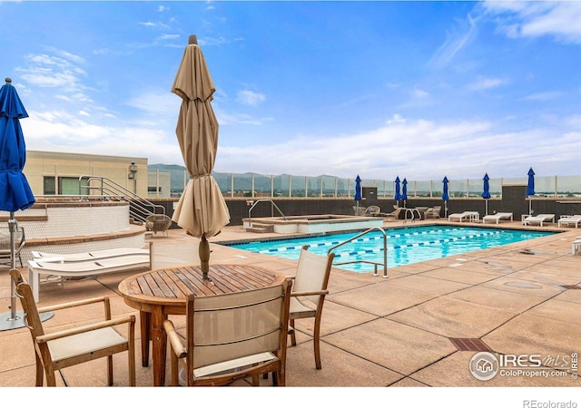 pool featuring a patio area, fence, a mountain view, and a hot tub