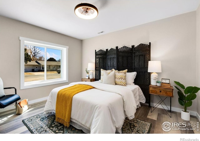 bedroom with visible vents, baseboards, and wood finished floors