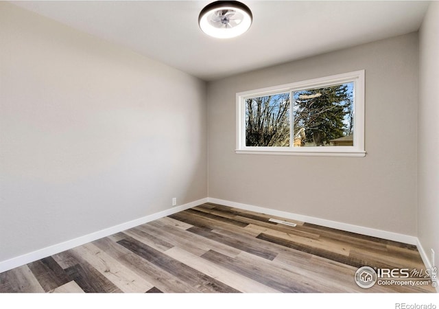 spare room with baseboards and wood finished floors