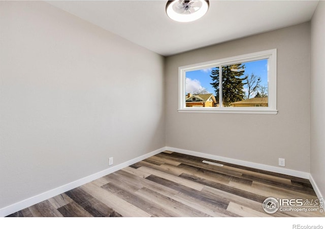 spare room featuring baseboards and wood finished floors