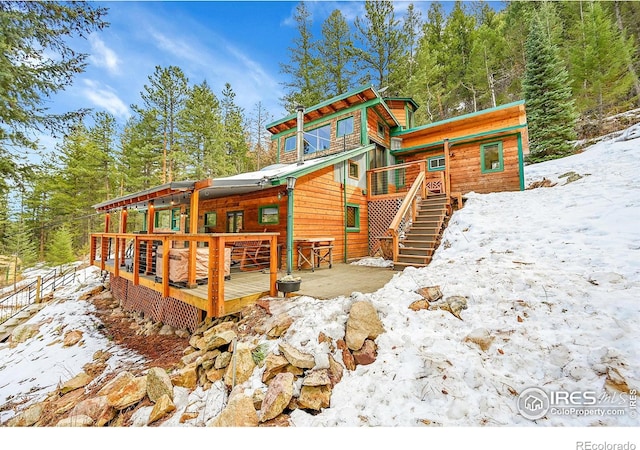 snow covered house with stairway and a deck