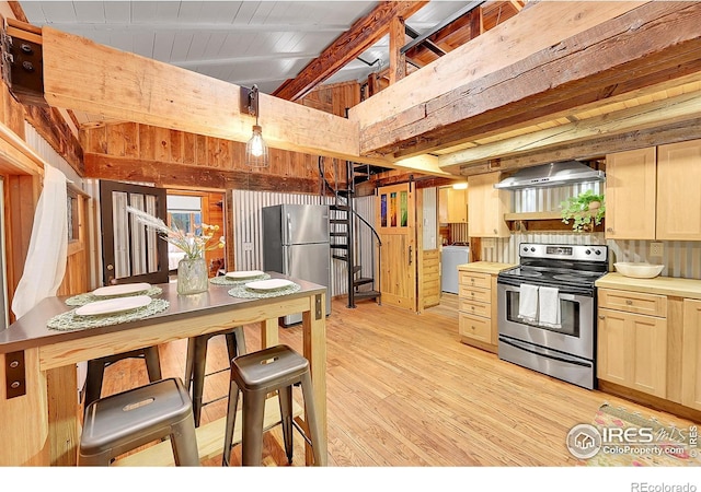 kitchen with stainless steel appliances, light countertops, light wood-style flooring, washer / dryer, and wall chimney exhaust hood