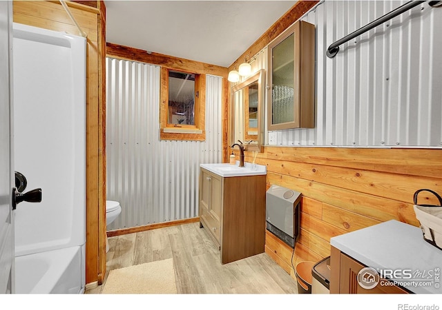 full bathroom with toilet, wood finished floors, vanity, and wooden walls