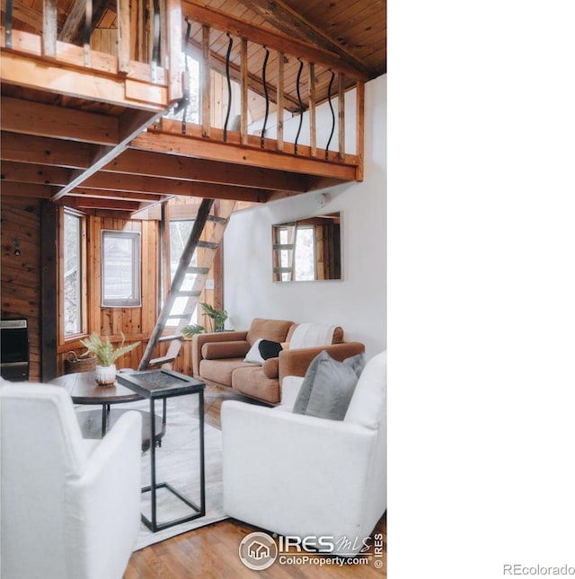 living room with wooden walls, wood finished floors, high vaulted ceiling, wooden ceiling, and beamed ceiling