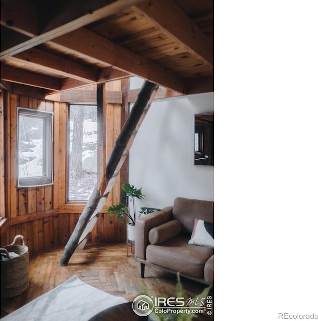 sitting room featuring parquet flooring, beam ceiling, and wooden walls