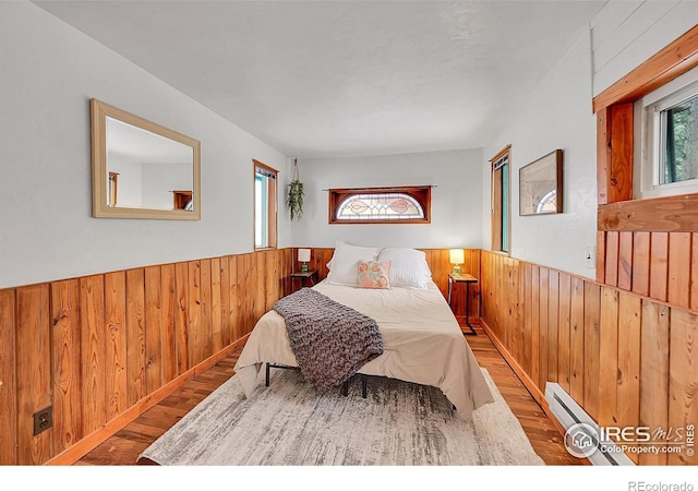 bedroom with a wainscoted wall, wood finished floors, and wooden walls