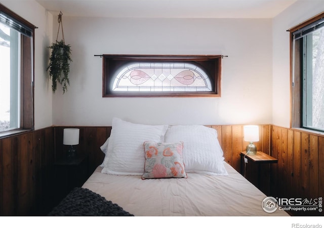 bedroom with wood walls and a wainscoted wall