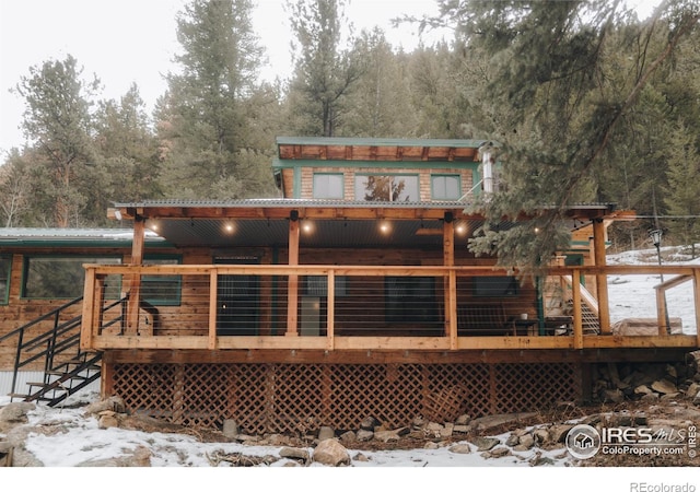 snow covered rear of property featuring stairway and a wooden deck