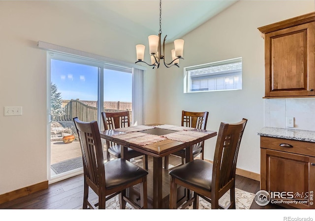 dining area featuring lofted ceiling, dark wood-style flooring, baseboards, and a notable chandelier