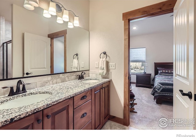 ensuite bathroom featuring double vanity, connected bathroom, and a sink