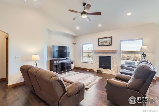 living room featuring vaulted ceiling, a stone fireplace, and wood finished floors