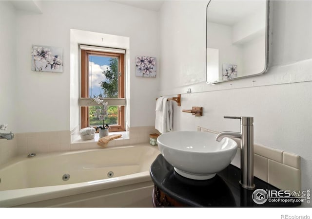 full bathroom featuring a tub with jets and a sink