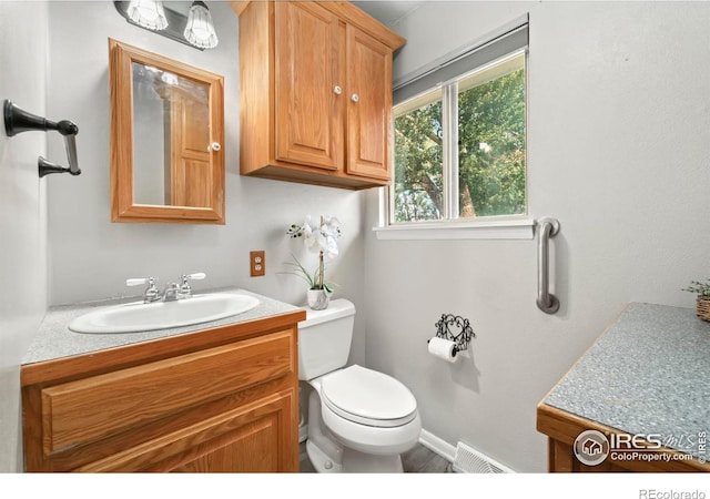 half bath featuring toilet, visible vents, and vanity